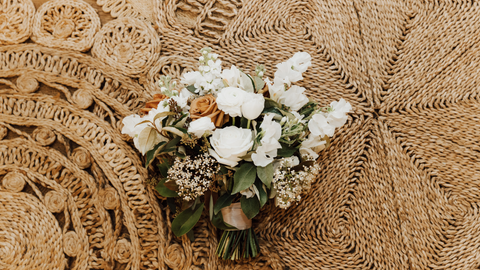 sage, tan, and white bridal bouquet on tan wicker basket