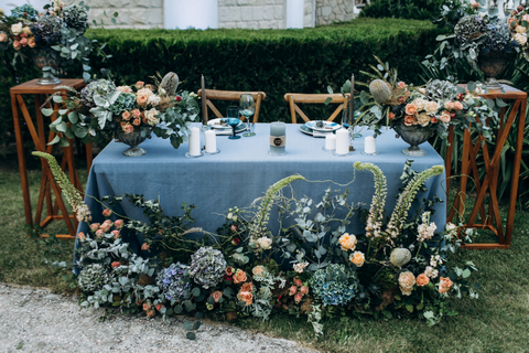 sweetheart table covered in blue table cloth and blue and pink flowers