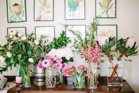 variety of greenery, focal, and filler flower in clear vases on a table