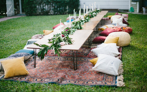 garden party with long table in the backyard with pillows as seats