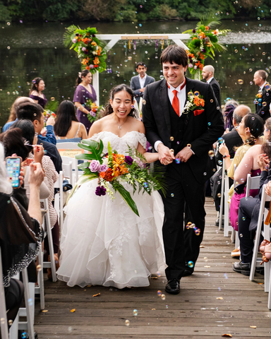 bride and groom walking down the aisle while bride is holding her tropical bridal bouquet