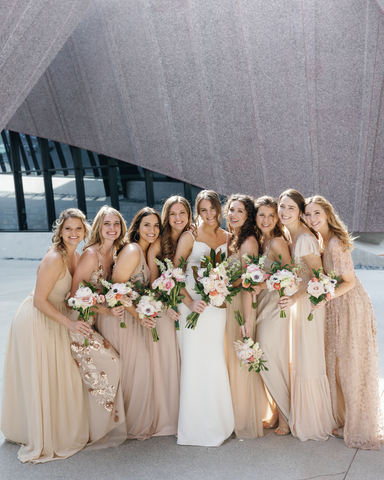 bride with bridesmaids in champagne colored dresses while all holding their bouquets