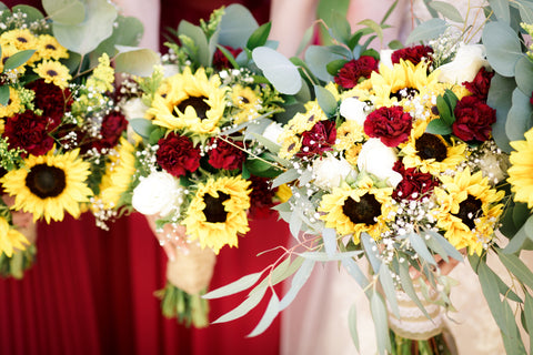 bridal bouquet made of sunflowers, burgundy carnations, and other small yellow and white flowers