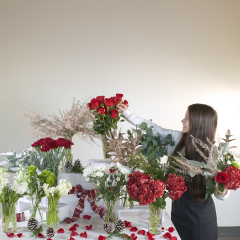 girl at holiday bouquet bar creating a DIY bouquet for Christmas