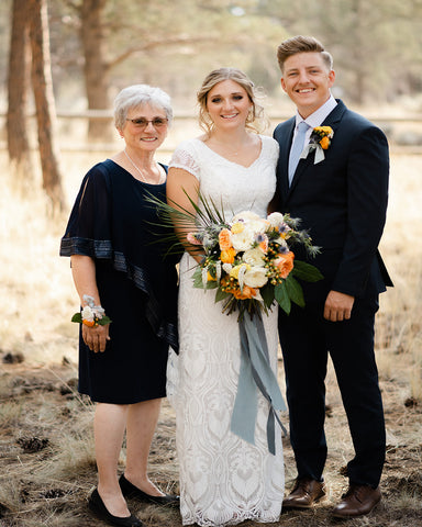 family member with bride and groom while bride holds bridal bouquet