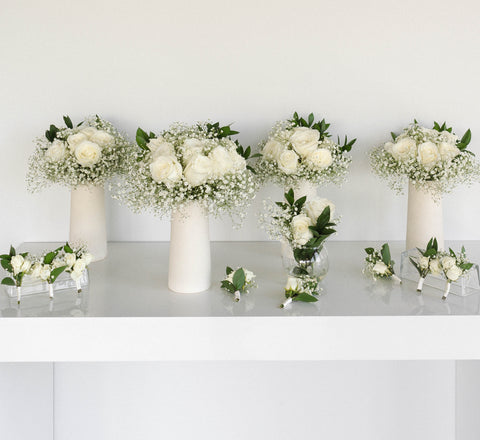 four vases with white flowers and corsages and boutonnieres