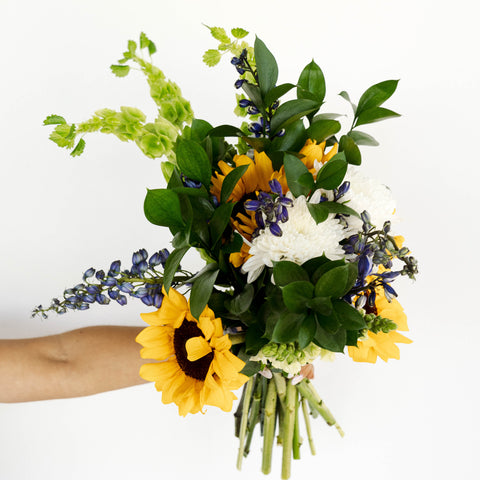 green and yellow spring flower arrangement being held in hand