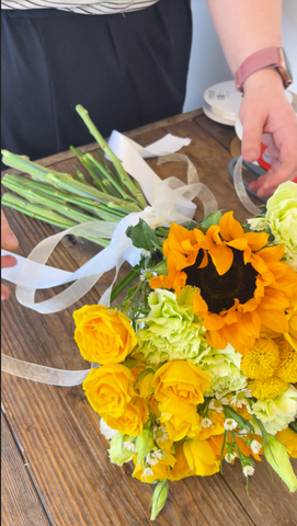 yellow bouquet being wrapped with white sheer ribbon