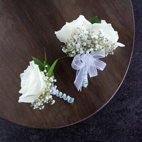 white rose boutonniere and corsage pair with babys breath and a white bow