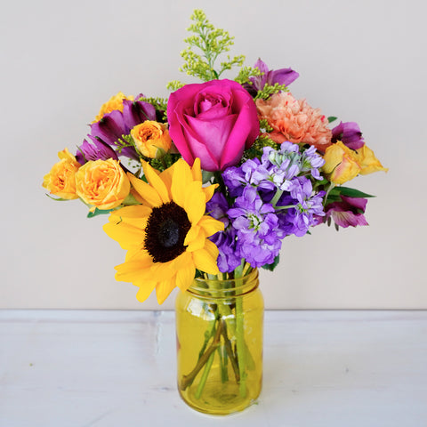 pink, yellow, and purple flowers in a yellow mason jar