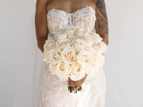 bride in lacy wedding dress holding a white rose bouquet