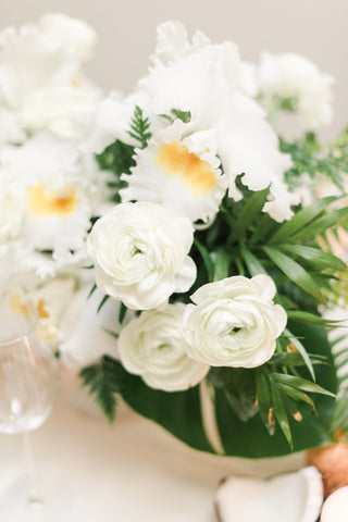 white ranunculus in a centerpiece with lush greenery