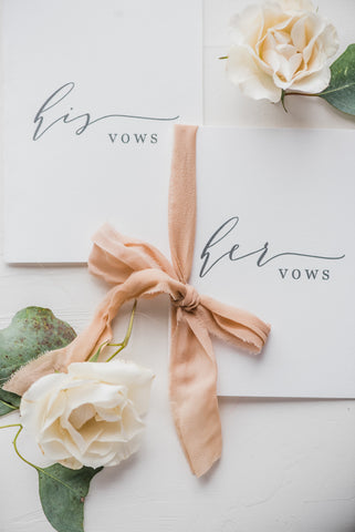 his and her vow books with pastel blooms and a pink bow