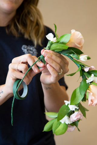 attaching pink and white flowers with greenery to flower crown