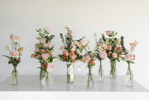 Eight peachy pink tall flower arrangements in clear vases