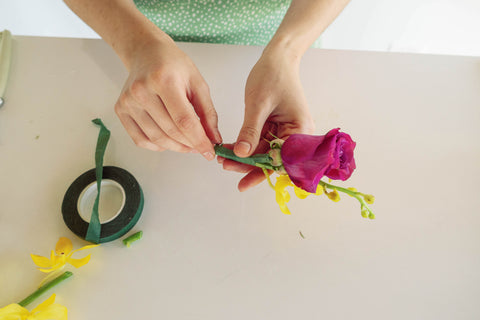 pink rose and yellow flower being taped together with floral tape