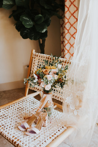 FiftyFlowers How To Style Toffee Roses and Possible Alternatives styled wedding shot with bridal bouquet and shoes in a chair containing toffee roses and toffee rose alternatives