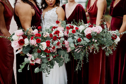 bridal and bridesmaids bouquets made of pink roses, burgundy carnations, and sage greenery