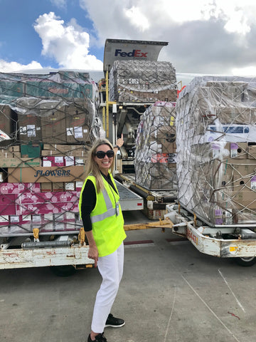 Liza Roeser in front of palette full of flower boxes getting loaded into a plane