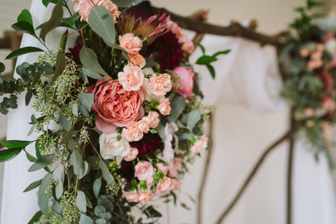 wedding archway with greenery, pink carnations, and other pink florals