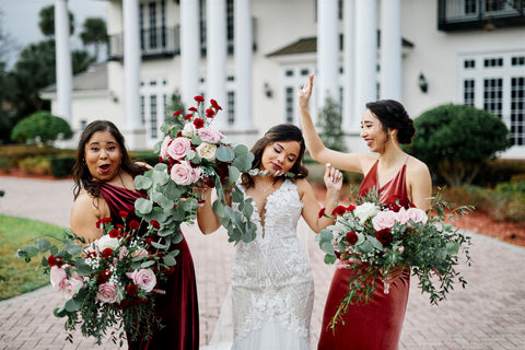 bride with bridesmaids holding bouquets having fun