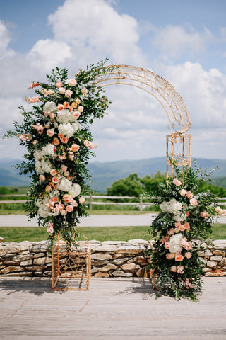 ceremony arch with greenery and pink flowers