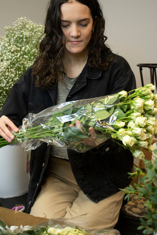 girl wearing black jacket taking plastic off of her white flowers she just received