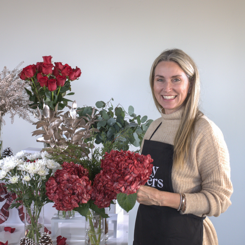 Liza Roeser at holiday bouquet bar creating Christmas arrangement