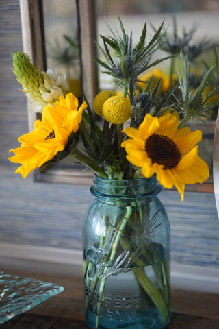 sunflower arrangement in a blue mason jar