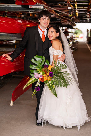 Bride with groom standing in front of red vehicle