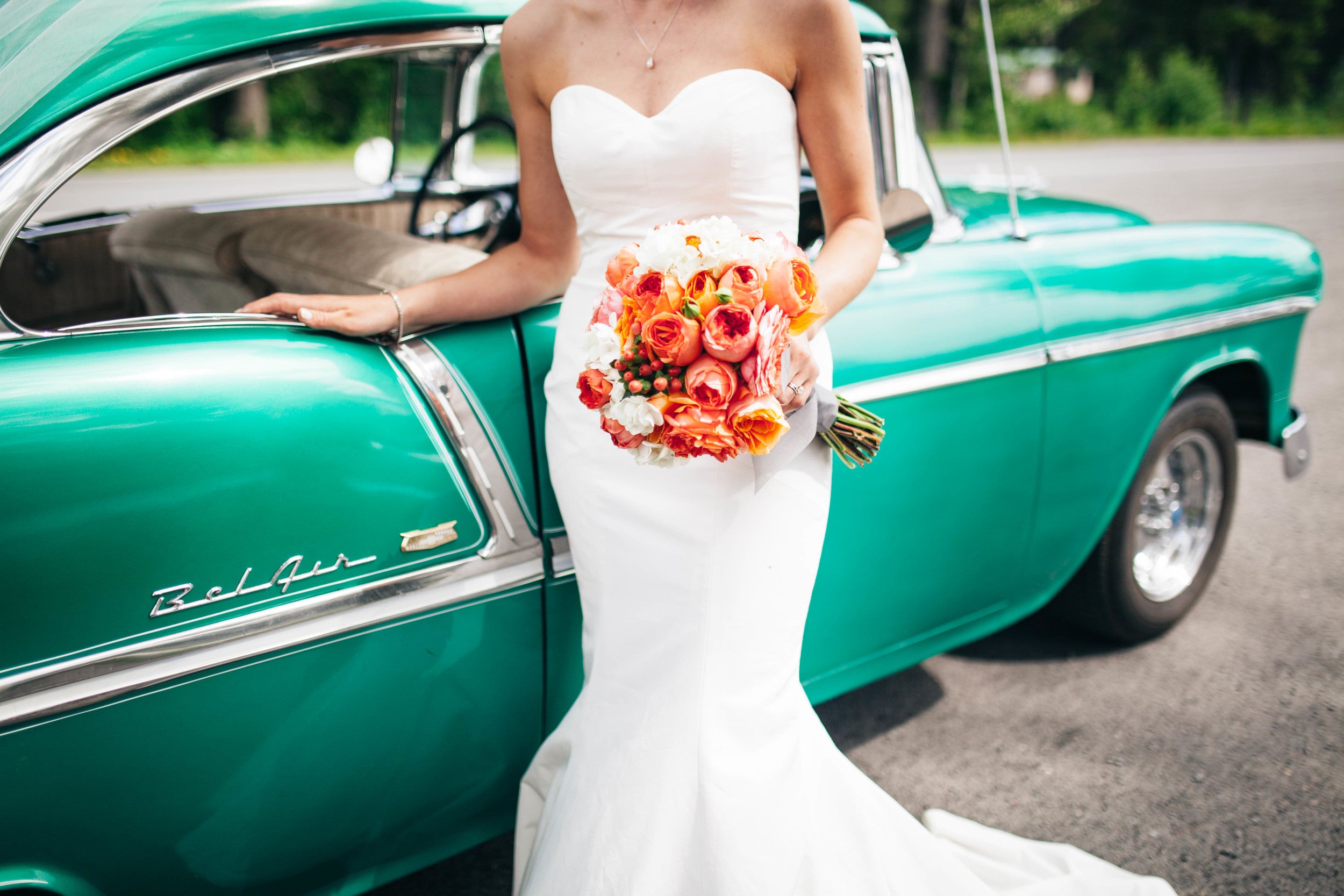 Bride holds round wedding bouquet with orange flowers