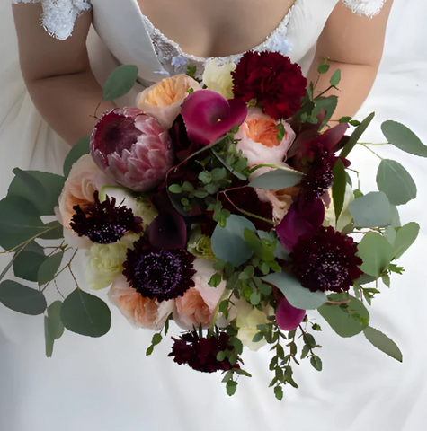 Bride holding flower bouquet with protea flower inside.