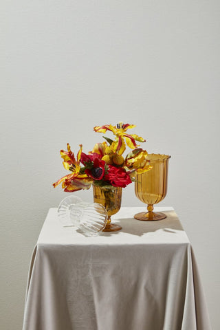 two yellow vases and one has a flower arrangement in it