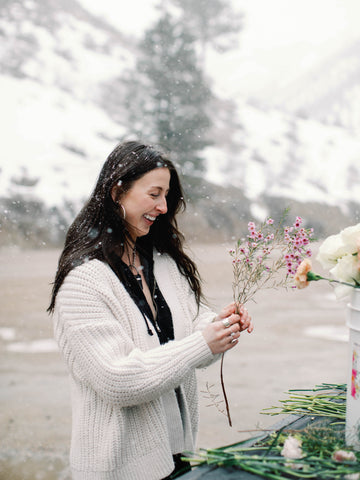 girl in the snow customizing a centerpiece with pink wax flowers