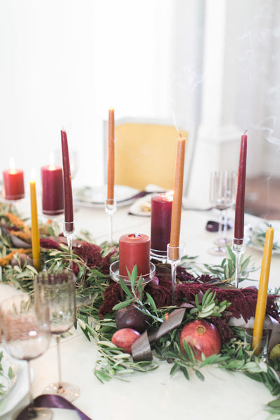 fall centerpiece with orange and red candles and a greenery garland