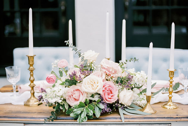 pink and white flower centerpiece with tall white candles on candle stand