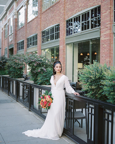bride holding bouquet while standing in front of brick building