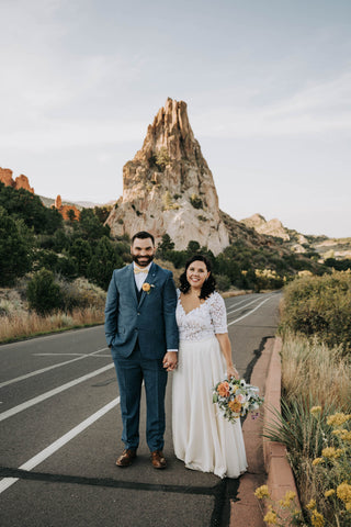 bride and groom walking on street in front of a mountain