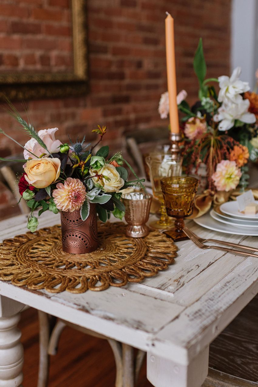 A cozy wedding table setting with bronze accents and fresh DIY flower arrangements