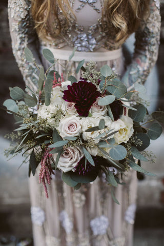 bride holding a bridal bouquet that is sage green, ivory, and burgundy