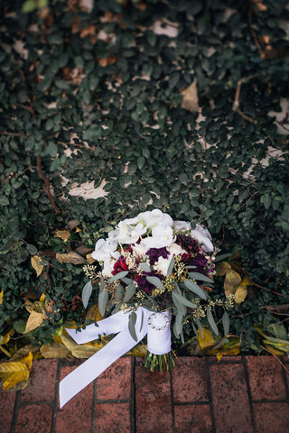 fall wedding bouquet in front of greenery wall
