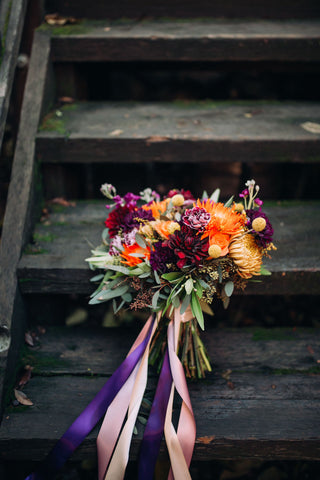 burgundy and orange fall wedding arrangement on black stairs
