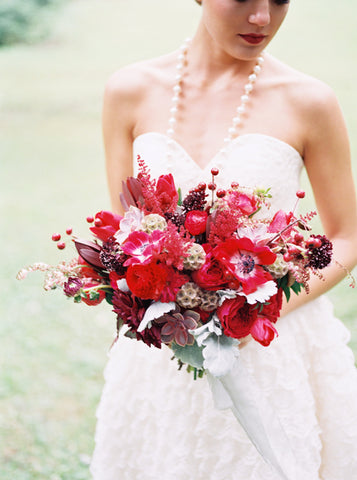 bride holding a red fall wedding arrangement