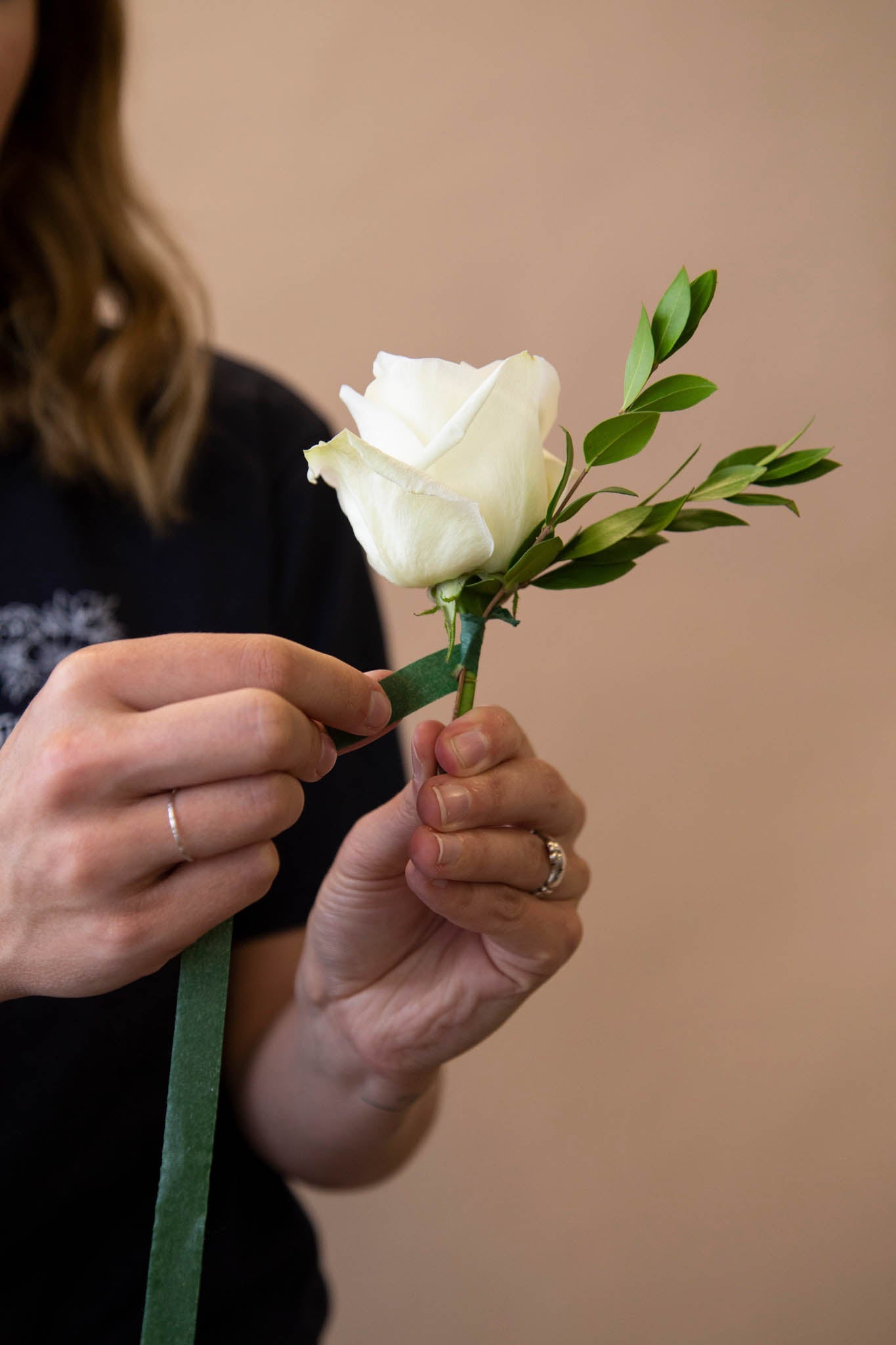 Start off DIY boutonniere by taping greenery behind focal flower