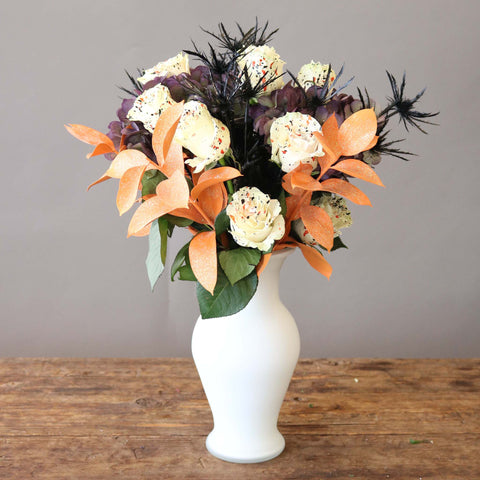 flower arrangement for halloween with white, orange, and black flowers in a white vase