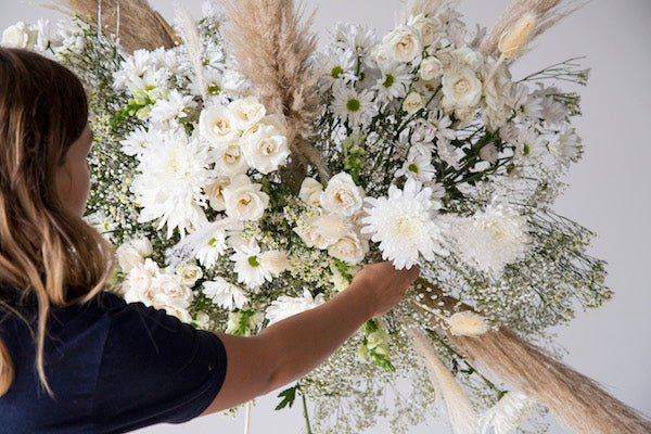 Adding spray roses to a hanging floral installation.