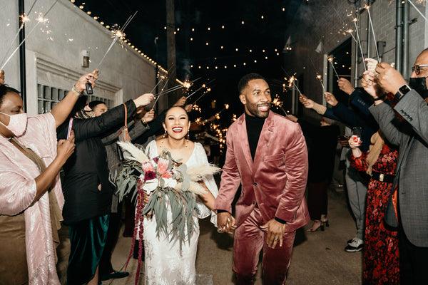 bride and groom walking through sparklers at a protea and velvet wedding