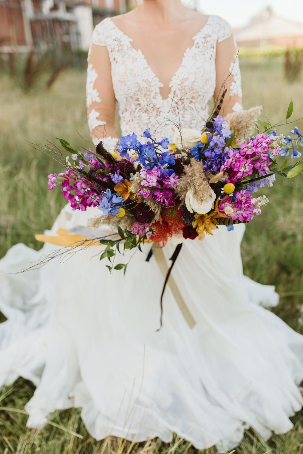 A bride holds a jewel toned wedding bouquet with berry pink and Very Peri periwinkle flowers