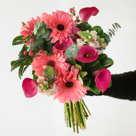 Bouquet with pink calla lilies and other pink flowers being held