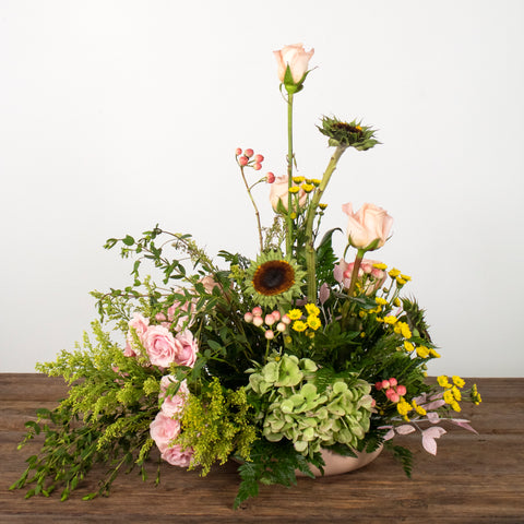 spring centerpiece with green and pink flowers on a wooden table